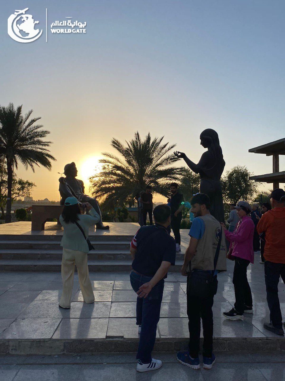 Travellers at the Shahrayar and Scheherazade statues in Baghdad at sunset
